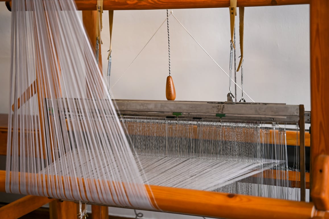 Traditional wooden loom with white weaving yarns